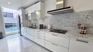 A modern kitchen with white cabinets, a gas stove, and a marble backsplash. - Dorisol IV - Luxury Apartment in La Vie (Funchal)