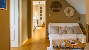 Un dormitorio acogedor con una cama grande, una mesita con una botella y una taza, y una puerta que da a otra habitación.