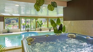Un jacuzzi con vistas a una piscina y amplios ventanales.