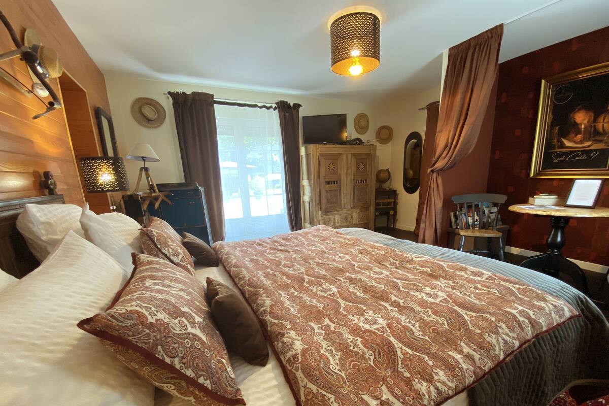 A spacious bedroom with a large bed, a television, and a desk with a chair.