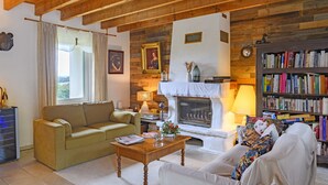 Un salón acogedor con sofá, mesa de centro, chimenea y estantería.