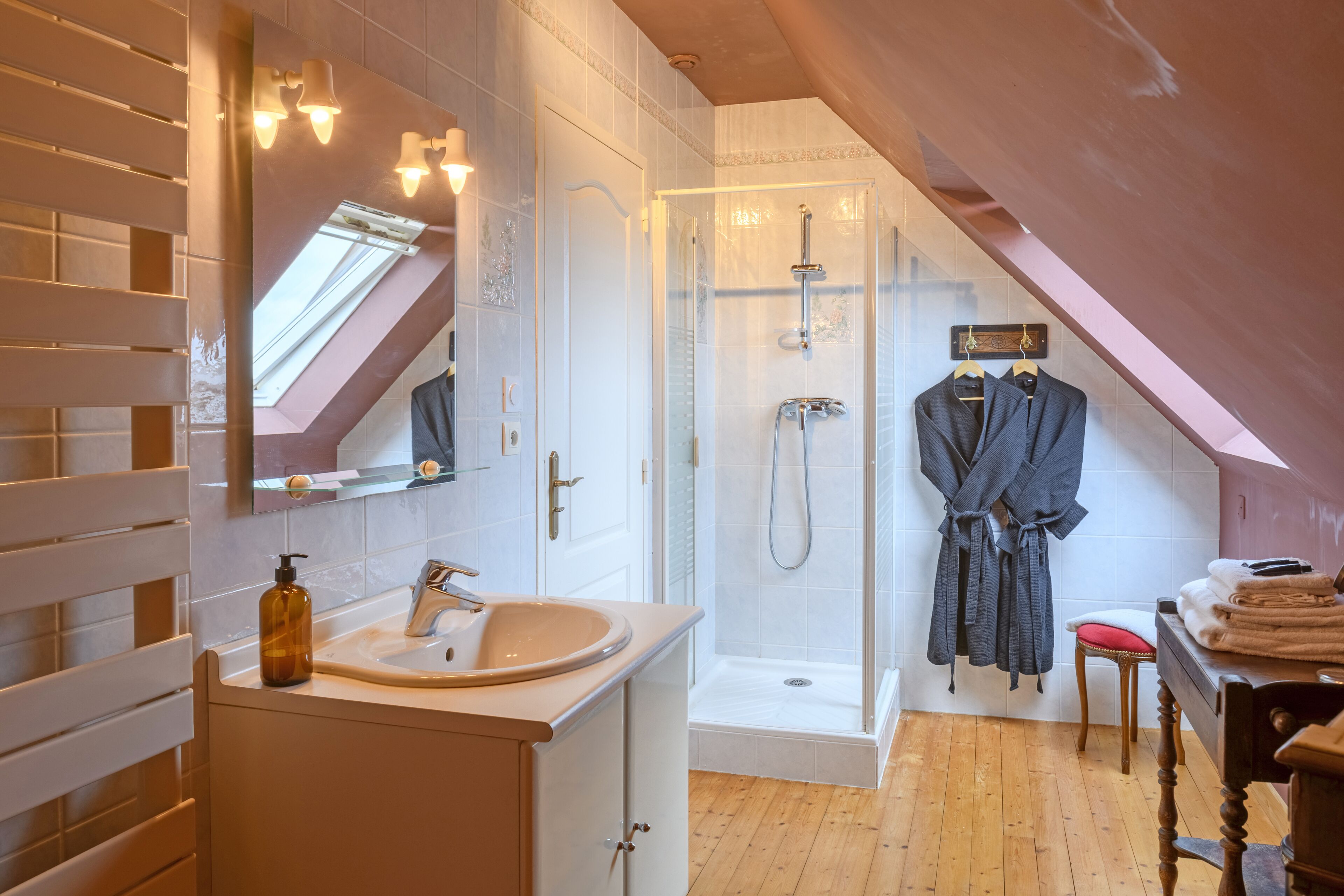 Un bagno moderno con una finestra a soffitto, una doccia a filo pavimento e un mobile lavabo con specchio.