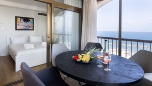 A room with a bed, a dining table with fruit and wine glasses, and a view of the ocean. - Grand Sea View Retreat by Sea N' Rent (Tel Aviv)