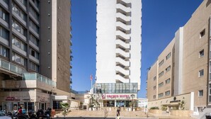 A hotel with a central staircase leading to the entrance, surrounded by modern buildings. - Grand Sea View Retreat by Sea N' Rent (Tel Aviv)