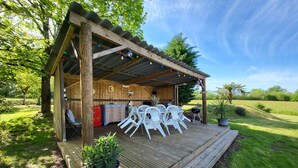 A wooden outdoor dining area with white plastic chairs, a grill, and a wooden deck. - Maison de Campagne Avec Piscine (Rives)