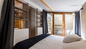 Un dormitorio con cama, un separador de listones de madera y vistas a través de una puerta corrediza de cristal.