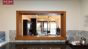 A kitchen with a wooden countertop, a large mirror, and a view into the dining area. - Prime select Sodic Eastown New Cairo (New Cairo)