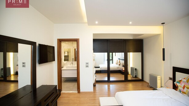 A modern hotel room with a large bed, a TV, a mirror, and a walk-in closet. - Prime select Sodic Eastown New Cairo (New Cairo)