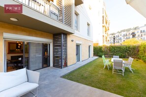 A modern apartment with a balcony, outdoor seating, and a well-maintained lawn. - Prime select Sodic Eastown New Cairo (New Cairo)