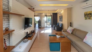 A modern living room with a flat-screen TV, wooden shelves, a sofa, and a coffee table. - Prime select Sodic Eastown New Cairo (New Cairo)