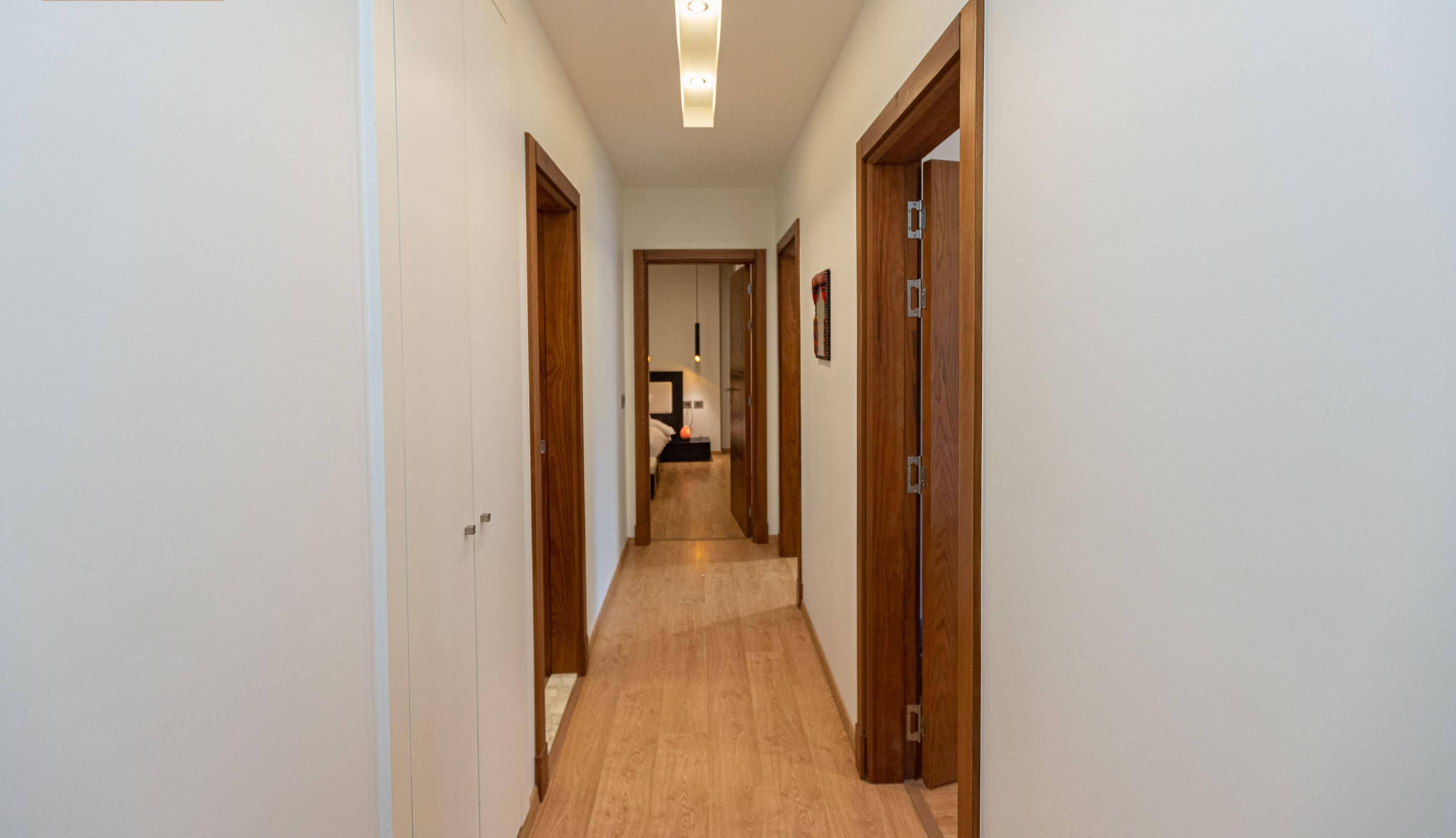A hallway with wooden doors and a light fixture on the ceiling.