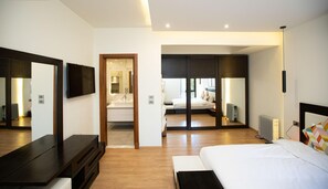 Une chambre d’hôtel moderne dotée d’un grand lit, d’une télévision, d’un miroir et d’un dressing.