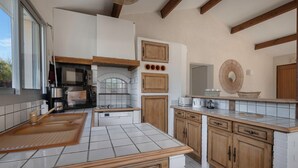 A modern kitchen with white tiles, wooden cabinets, and a built-in oven. - Préfailles - House 6P - 200m from the beaches (Préfailles)
