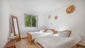 A bedroom with two single beds, a large mirror, a wicker chest, and a window with a view of greenery. - Préfailles - House 6P - 200m from the beaches (Préfailles)