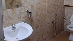 Un baño con pared de mármol, un lavabo, un espejo, una ducha y un inodoro.