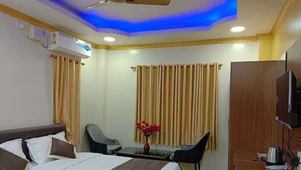 Una habitación de hotel con una cama, un escritorio, una silla, un televisor y un ventilador de techo.