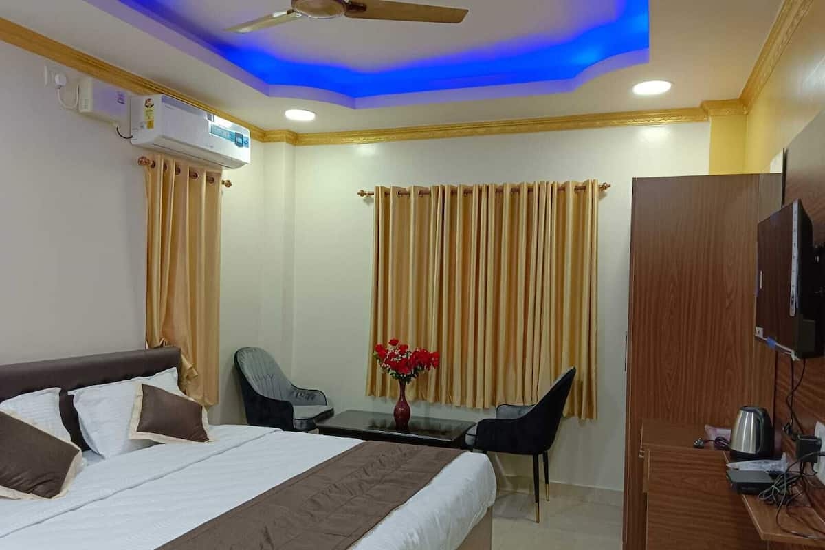 A hotel room with a bed, a desk, a chair, a television, and a ceiling fan.
