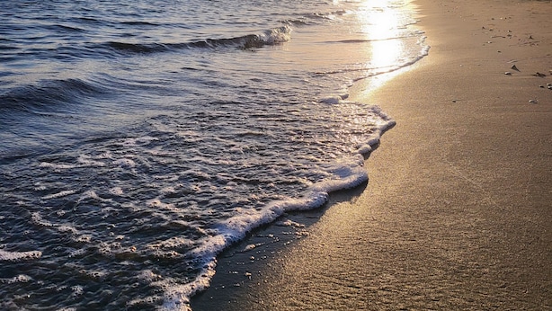 Una playa con olas y un atardecer.