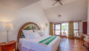 Une chambre à coucher avec un lit, deux lampes de chevet, un ventilateur de plafond, une fenêtre avec des rideaux et une vue sur l’extérieur.