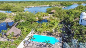 Een resort met een zwembad, palmbomen en uitzicht op een rivier.
