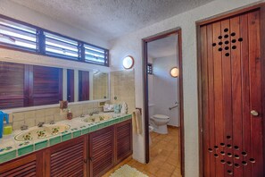 Une salle de bain avec deux lavabos, un miroir et des toilettes.
