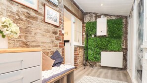 Una stanza con un muro in mattoni, un letto con un tappeto decorato, un termosifone bianco e quadri appesi alle pareti.