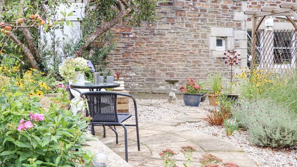 Un edificio in pietra con un patio giardino, che include un tavolo, sedie e piante in vaso.