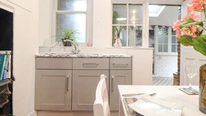 Una cucina con un piano di lavoro bianco, mobili grigi e una finestra vista esterna.