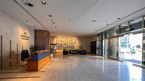 Een ruime lobby met een receptiebalie, een zithoek en een grote glazen gevel.