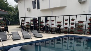 A swimming pool with lounge chairs and potted plants. - The Address Hotel (Abuja)
