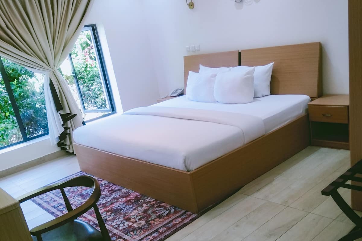 Une chambre à coucher comprenant un grand lit, un bureau, une chaise, une table de chevet et un élément décoratif mural.