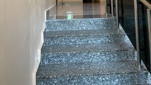 A modern hotel lobby with a marble staircase, decorative wall art, and a glass railing. - The Address Hotel (Abuja)