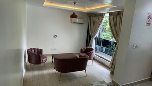 A modern living room with a dining table, two armchairs, a ceiling light, and a large window with curtains. - The Address Hotel (Abuja)