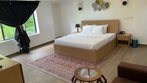 A modern bedroom with a large bed, bedside tables, a small table, and a chair. - The Address Hotel (Abuja)