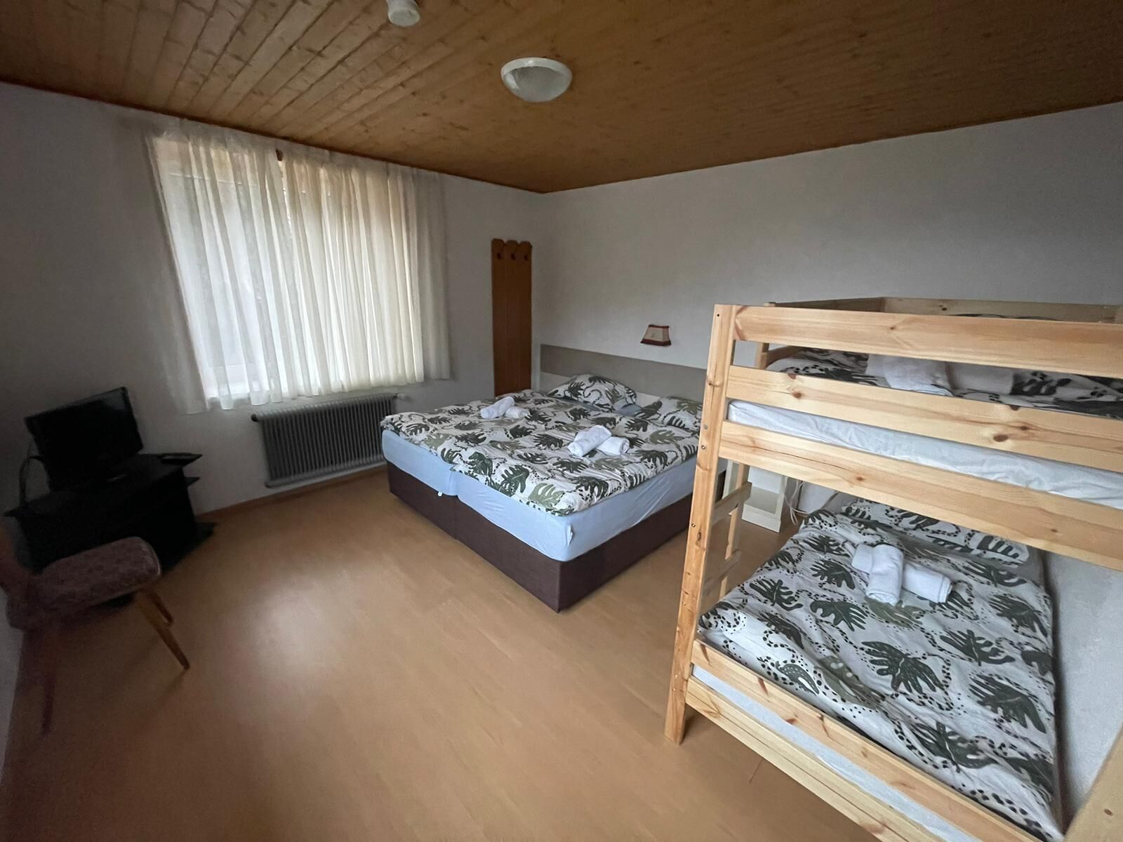 Et soveværelse med køjeseng, en enkeltseng, et skrivebord og en stol.