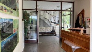 A reception area with a wooden desk, a sofa, and a staircase leading to an upper floor. - Gasthof Lublass (Matrei in Osttirol)