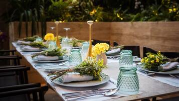 A long dining table set with plates, cutlery, and decorative glass jars with flowers.