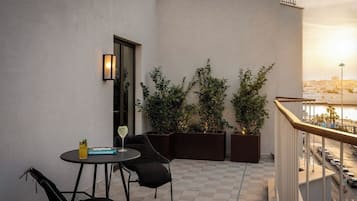 A balcony with a table and chairs, potted plants, and a view of the cityscape.