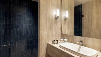 A modern bathroom with a large mirror, a sink, and a shower area.