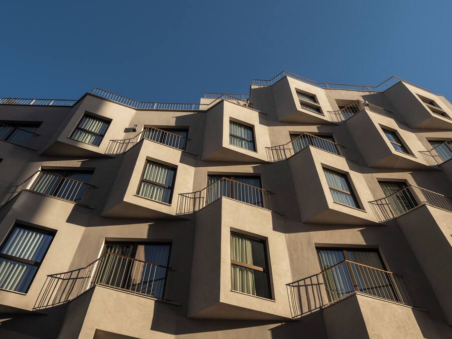 Un edificio de varios pisos con un diseño arquitectónico angular distintivo, que incluye balcones y ventanas amplias.