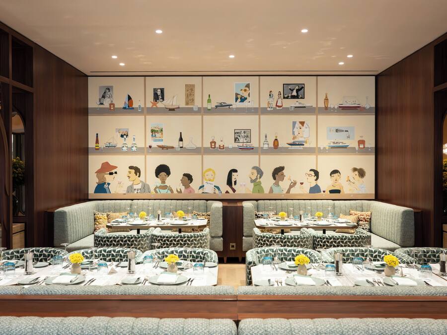 Un restaurant doté d’une longue table et de banquettes, dont les murs sont ornés d’œuvres d’art et dont l’intérieur présente un design moderne.