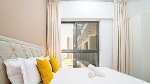 A hotel room with a large bed, white bedding, and yellow pillows. - Tanin-Beautiful and Modern Apartment with Huge Space (Dubai)
