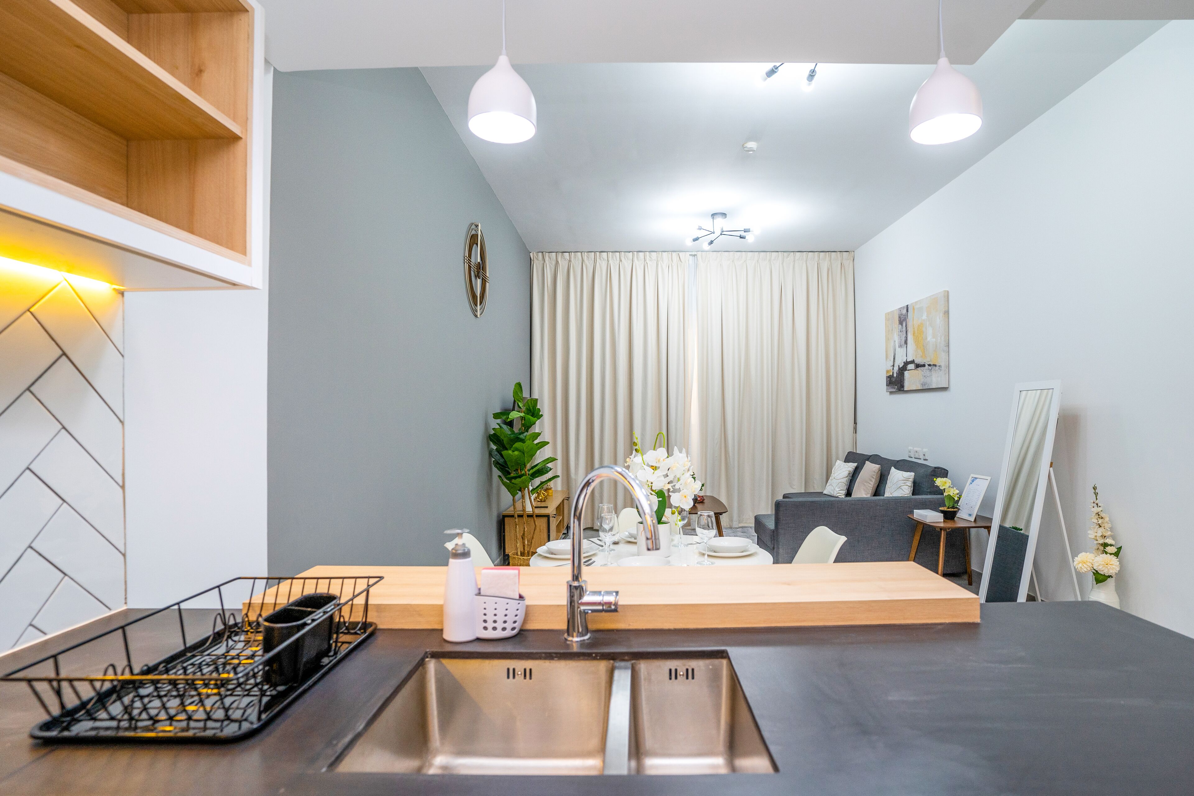 Une cuisine moderne dotée d’un évier à deux bacs, d’un plan de travail en bois et de luminaires suspendus.