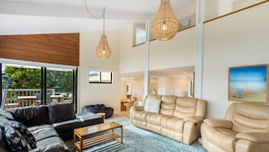 Un salón amplio con un ventanal grande, un sofá color beige, un sofá de cuero negro y una mesa de centro de madera.