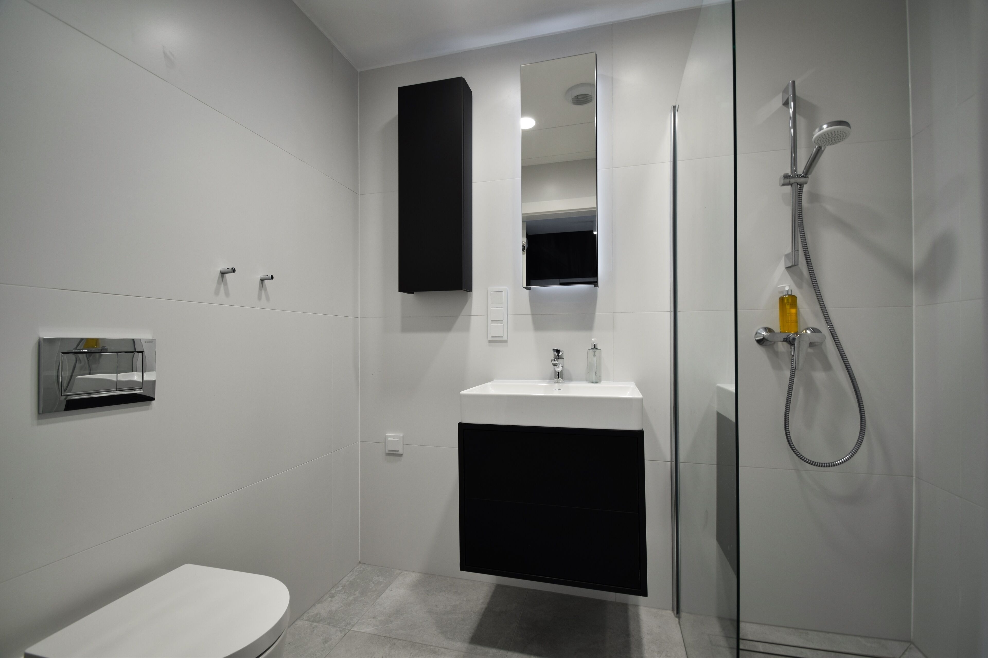 Un baño moderno con inodoro, lavabo, espejo y ducha.