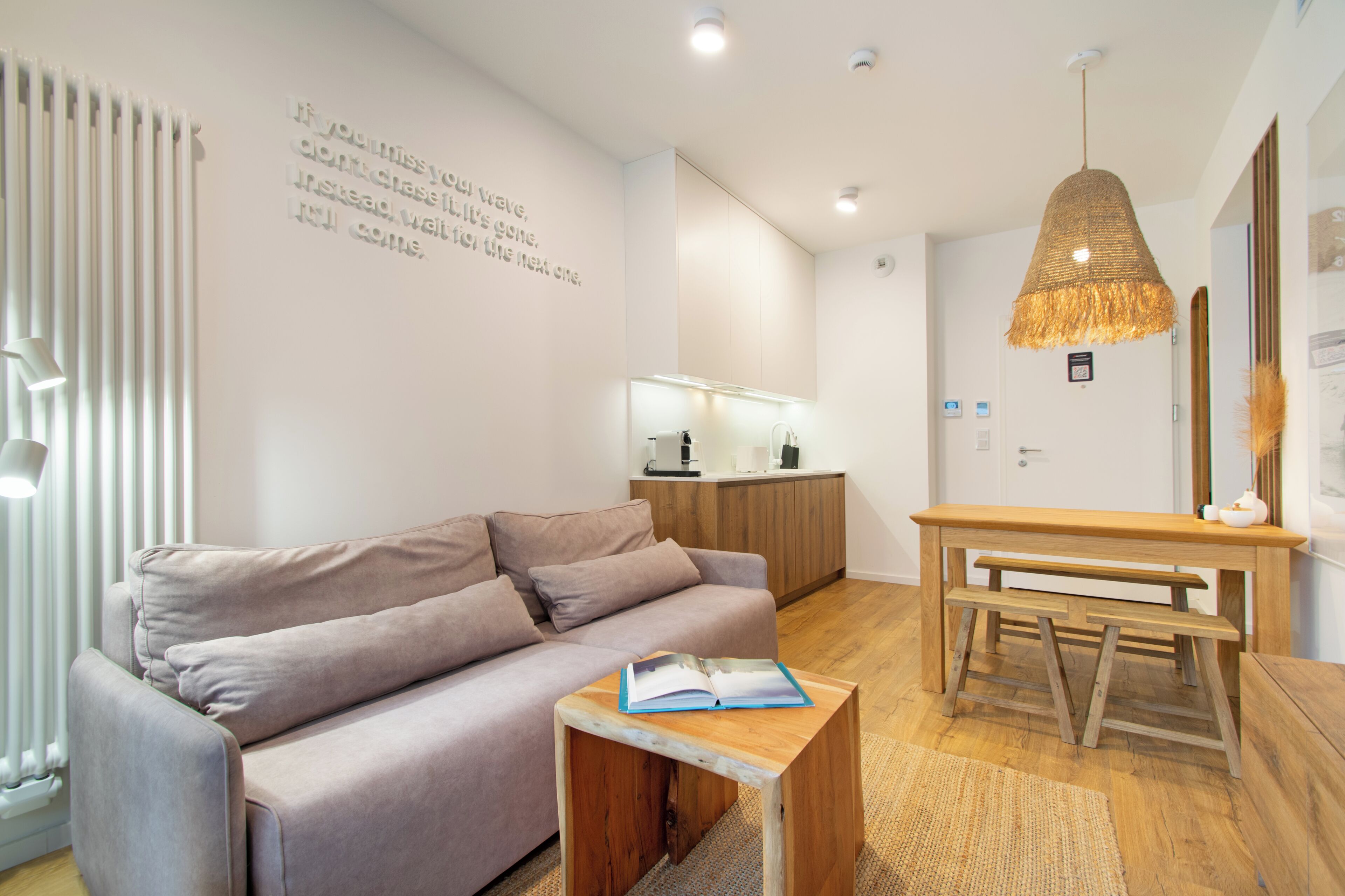 Una sala moderna con un sofá, una mesa de centro de madera y una lámpara colgante.