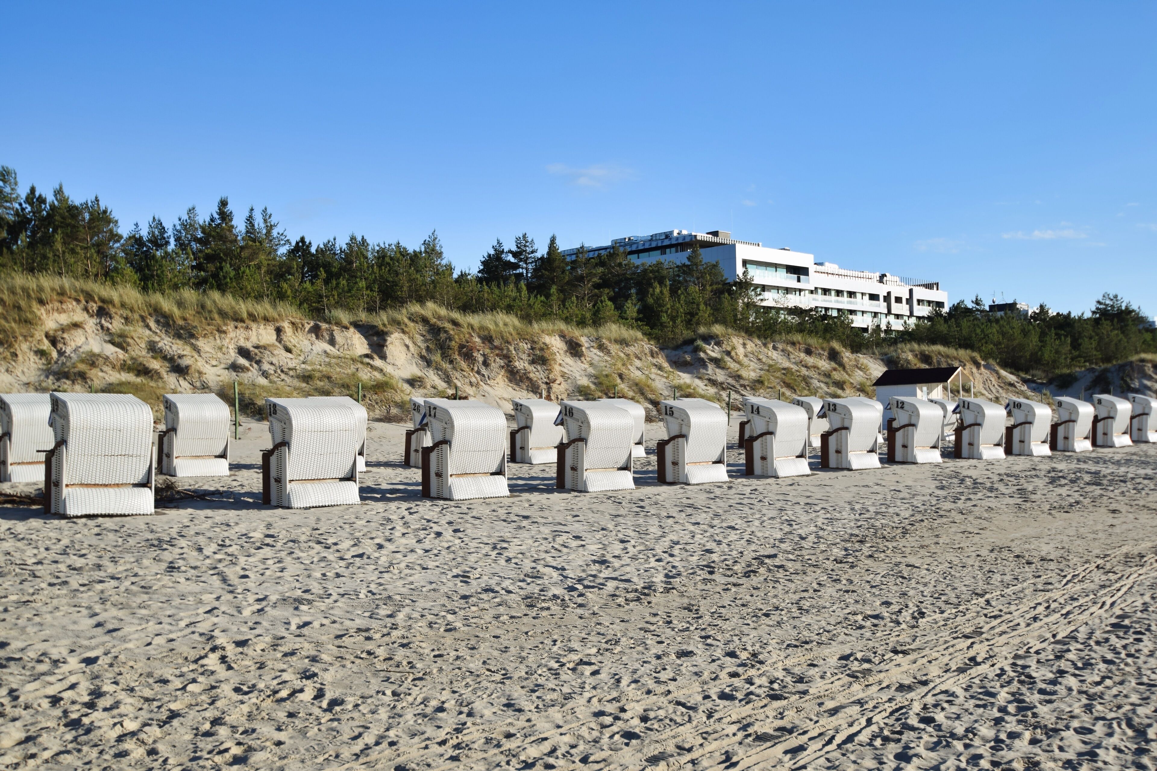 A beach with sand dunes and a building in the background.