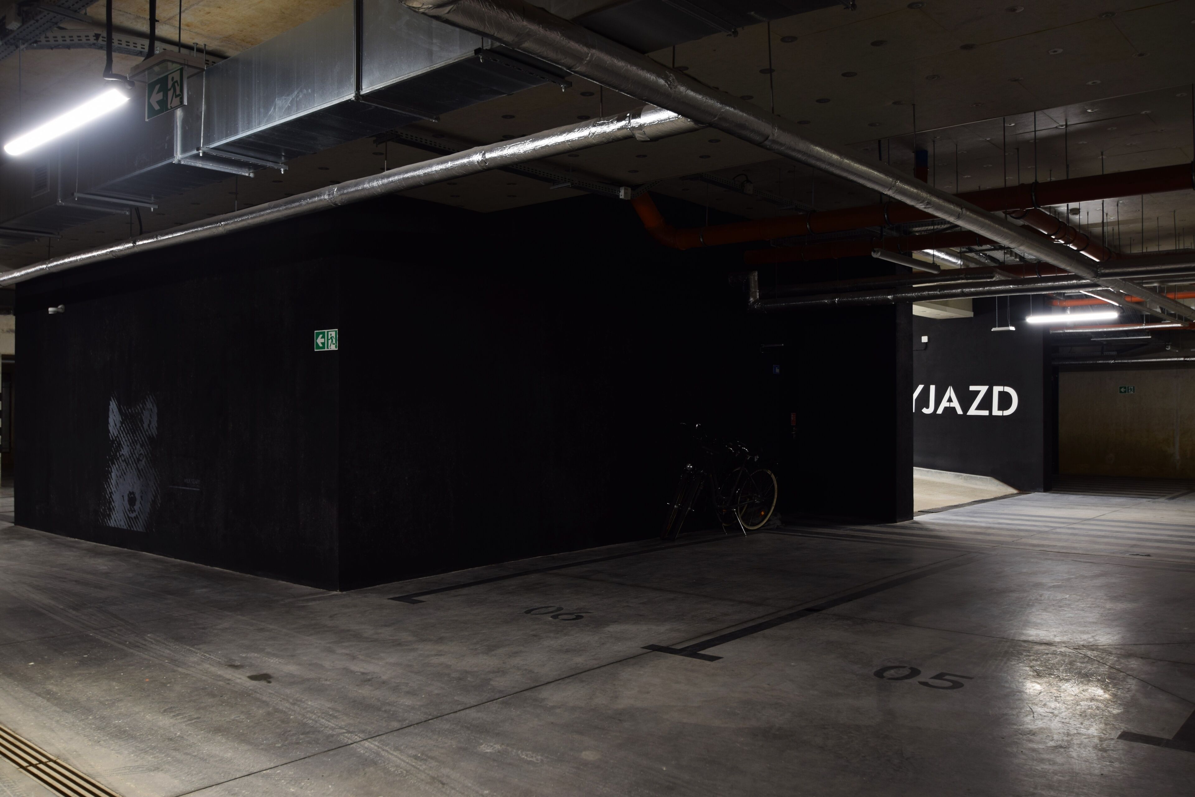 A parking garage with a black structure labeled "JAZD" and a bicycle parked nearby.