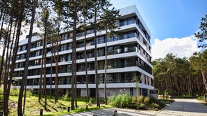 A multi-story building with a modern architectural design, surrounded by a forested area. - RentPlanet - Shellter (Trzebiatow)