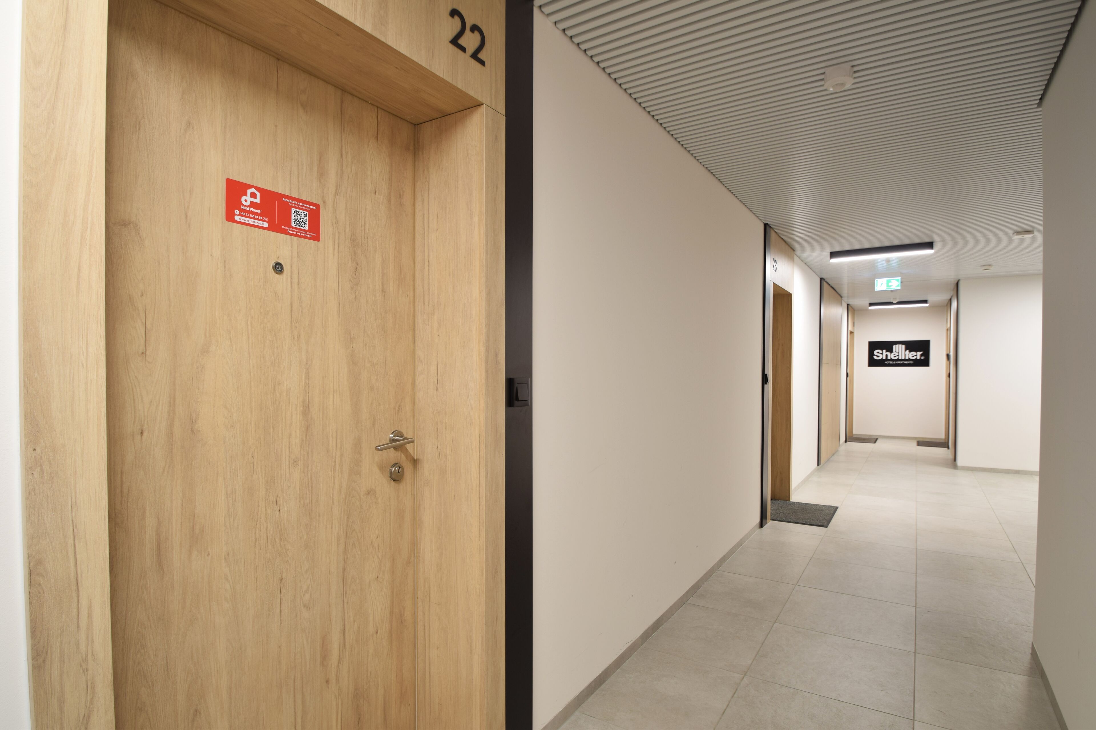 Un pasillo con una puerta de madera con el número 22 y un letrero que indica una habitación de 'Refugio'.